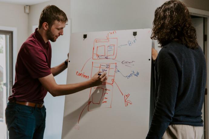 man drawing on dry-erase board